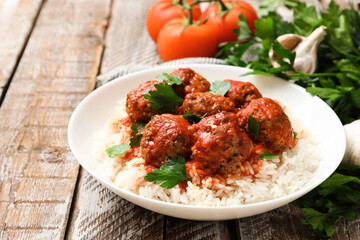 Tasty meatballs with sauce, rice and products on wooden table, closeup