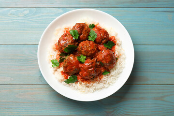 Tasty meatballs with sauce and rice on light blue wooden table, top view