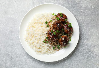 Delicious rice with meatballs, sauce and green onions on grey table, top view
