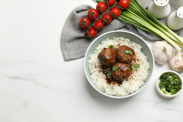 Delicious rice with meatballs, sauce and green onions on white marble table, flat lay. Space for text