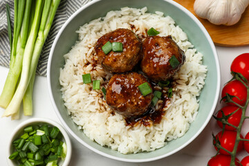 Delicious rice with meatballs, sauce and green onions on white table, flat lay