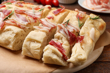Slices of delicious focaccia bread with bacon and rosemary on wooden table, closeup