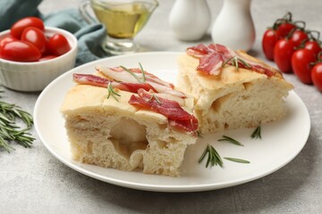 Pieces of delicious focaccia bread with bacon served on grey table, closeup