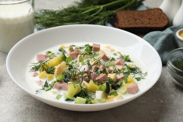Delicious okroshka soup in bowl on grey textured table, closeup