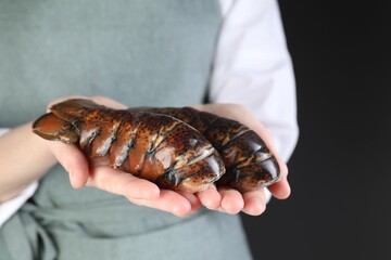 Woman with raw lobster tails on black background, closeup