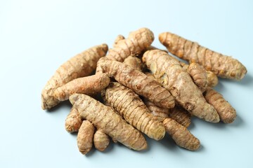 Pile of tumeric rhizomes on light blue background, closeup