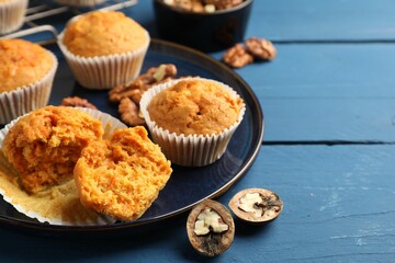 Tasty carrot muffins and walnuts on blue wooden table, closeup. Space for text