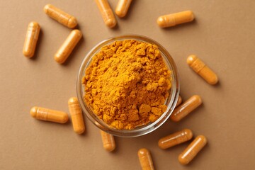 Turmeric capsules and powder on beige background, flat lay