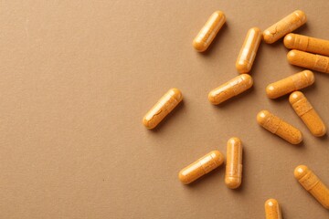 Turmeric capsules on beige background, flat lay. Space for text