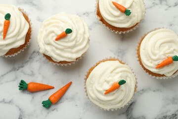 Delicious carrot cupcakes on white marble table, flat lay