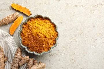 Aromatic turmeric powder in bowl and fresh roots on light grey table, flat lay. Space for text