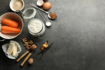 Different ingredients for making carrot cake and kitchenware on dark textured table, flat lay. Space for text