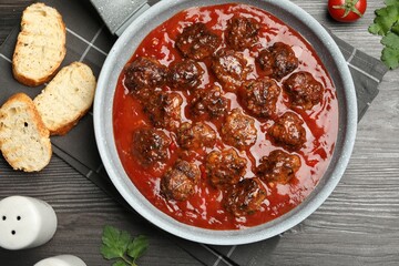 Delicious meatballs with tomato sauce served on wooden table, flat lay