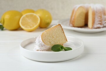Piece of delicious lemon cake with powdered sugar and mint on white wooden table, closeup