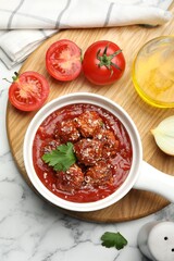 Delicious meatballs with tomato sauce, parmesan cheese and parsley served on white marble table, flat lay