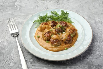 Delicious meatballs with gravy cream sauce, herbs and arugula served on grey table