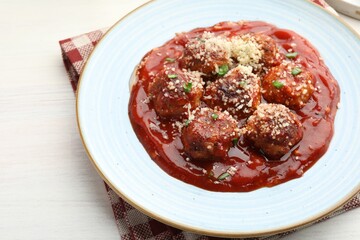 Delicious meatballs with tomato sauce, parmesan and herbs in on white wooden table, closeup