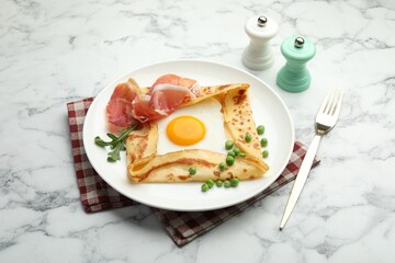 Delicious crepe with egg, bacon, arugula and green peas on white marble table