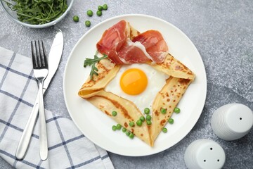 Delicious crepe with egg, bacon, arugula and green peas on grey table, flat lay
