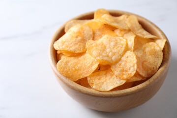 Tasty potato chips in bowl on white table, closeup. Space for text