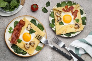 Delicious crepes with eggs, bacon and mushrooms served on grey table, flat lay. Breton galette