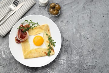 Delicious crepe bretonne with bacon and arugula served on grey textured table, flat lay. Space for text