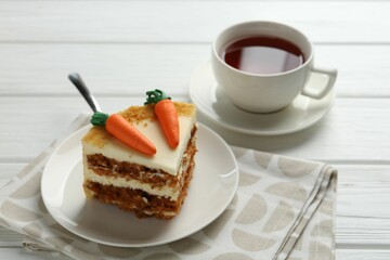 Piece of delicious homemade carrot cake with tea on white wooden table