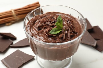 Tasty pudding with mint and pieces of chocolate on white table, closeup