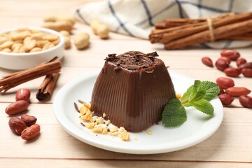 Tasty chocolate pudding with peanuts and mint on white wooden table
