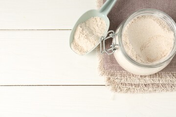 Brown rice flour on white wooden table, flat lay. Space for text