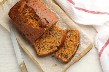 Homemade carrot cake with nuts and knife on white wooden table, top view