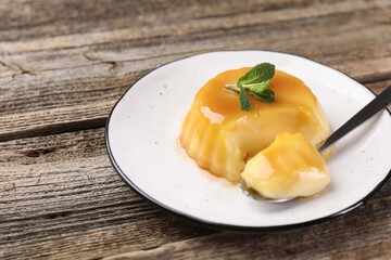 Delicious pudding with caramel sauce and mint served on wooden table, closeup. Space for text