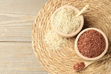 Different sorts of raw brown rice on wooden table, top view. Space for text