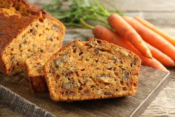 Homemade carrot cake with nuts and vegetables on wooden table, closeup