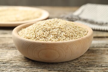 Brown rice in bowl on wooden table, closeup