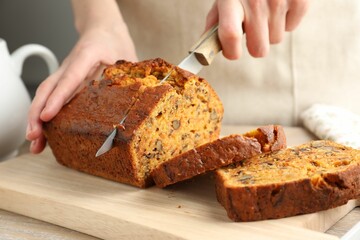 Woman cutting homemade carrot cake at table, closeup
