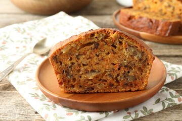 Cut homemade carrot cake with nuts and spoon on wooden table, closeup
