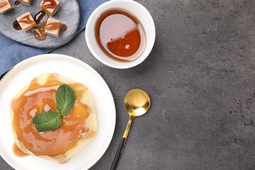 Delicious pudding with caramel sauce and mint served on gray textured table, flat lay. Space for text