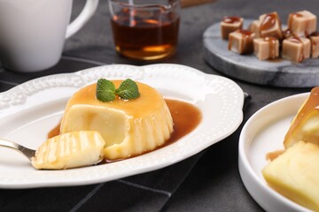Delicious pudding with caramel sauce and mint served on gray table, closeup