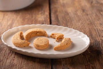 Studio shot photo of traditional Turkish sweets called Kavala Kurabiyesi, Kavala Cookies or Edirne Almond Cookies made with almonds and butter on white porcelain plate and white tin box in the 
