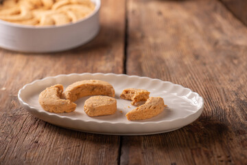 Close up studio shot photo of traditional Turkish sweets called Kavala Kurabiyesi, Kavala Cookies or Edirne Almond Cookies made with almonds and butter on white porcelain plate and white tin box 