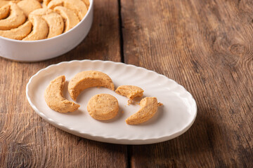 Studio shot photo of traditional Turkish sweets called Kavala Kurabiyesi, Kavala Cookies or Edirne Almond Cookies made with almonds and butter on white porcelain plate and white tin box in the 
