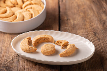 Studio shot photo of traditional Turkish sweets called Kavala Kurabiyesi, Kavala Cookies or Edirne Almond Cookies made with almonds and butter on white porcelain plate and white tin box in the 