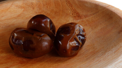 Close up 3 pieces dates fruit served on wooden plate