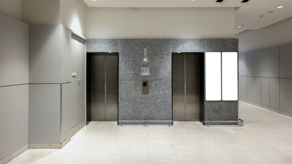 elevator entrance with modern architecture, empty lobby with metal lift doors and blank advertisement screen, contemporary office or commercial building interior design with clean lighting