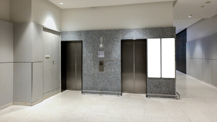 elevator entrance with modern architecture, empty lobby with metal lift doors and blank advertisement screen, contemporary office or commercial building interior design with clean lighting
