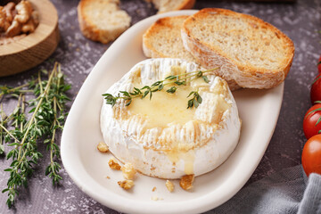 Plate of tasty baked Camembert cheese on grey background