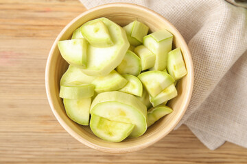Bowl with pieces of fresh green zucchini on wooden background