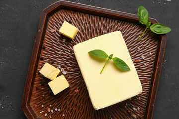 Tray with fresh butter and basil on black background
