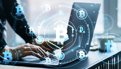 Person working on laptop with Bitcoin hologram icons.